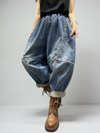 Model walking in oversized patchwork denim balloon pants with cuffed hems.