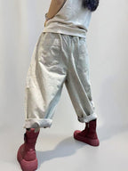 Side view of oversized drop crotch denim pants with rolled cuffs.