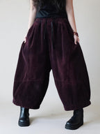 Oversized burgundy corduroy harem pants with cropped balloon legs.