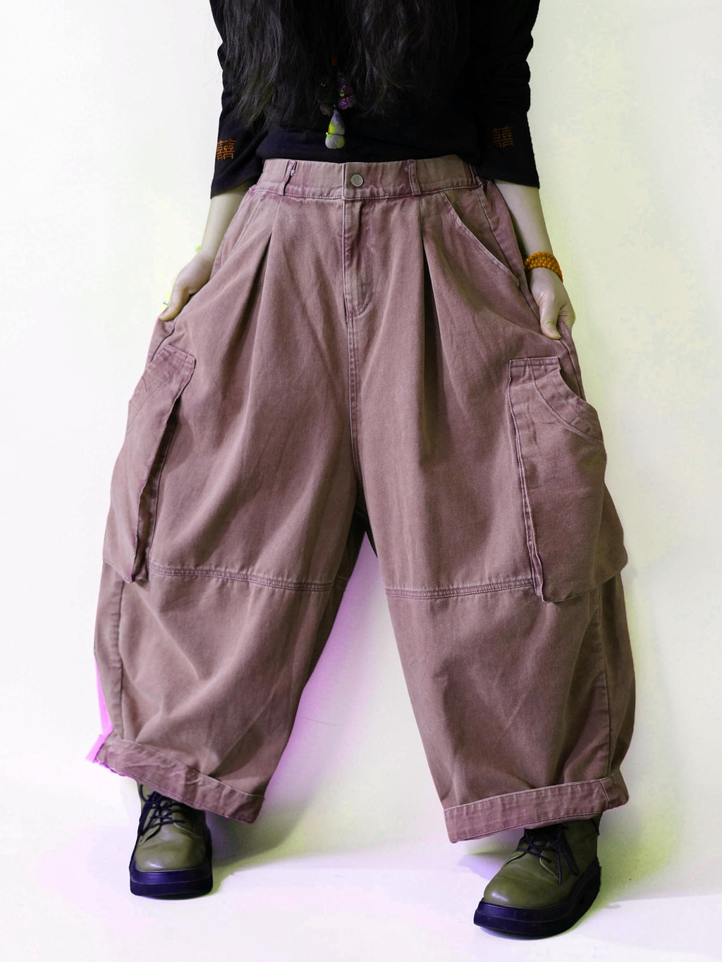 Side view of oversized dusty pink cargo balloon pants with a high waist.