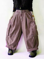 Side view of oversized dusty pink cargo balloon pants with a high waist.
